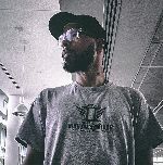 Aaron Rouselle Pictured here in Sepia Colored Photo with Brown Skin, Clear-White Glasses, Brown hair, Black Hat and Grey Shirt with the Words Pops Culture Iron Sharpens Iron T-shirt.