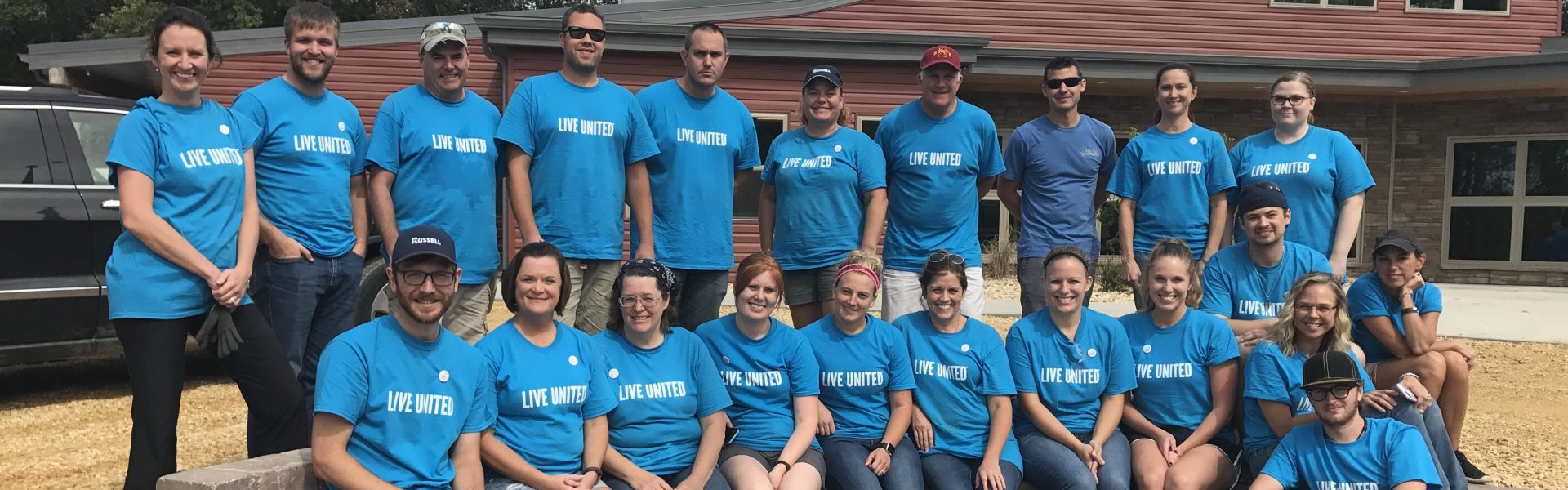 Volunteers, men and women with short brown hair and brown eyes, wearing blue t-shirts that say live united in white lettering.